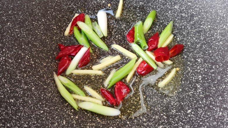 鱿鱼炒芹菜,炒锅内倒适量的食用油烧热，下入姜丝、葱段和干红辣椒炒香。