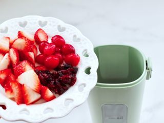 蔓越莓草莓花茶饮,榨汁杯里先放入蔓越莓果和草莓，加入蜂蜜。