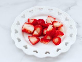 蔓越莓草莓花茶饮,草莓摘洗干净后，用刀切成小块。