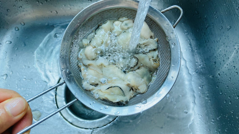 生蚝煎蛋,生蚝放在漏勺里用流动的水冲洗干净再控干水分