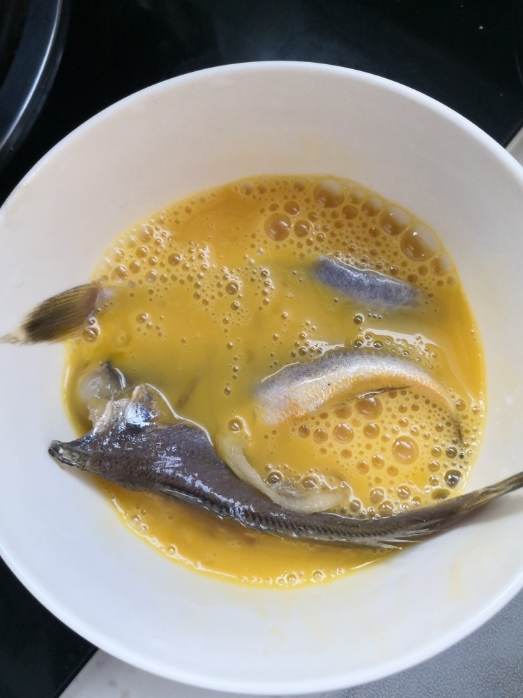 油炸黄花鱼,将腌制好的黄花鱼放入准备好的鸡蛋液中。