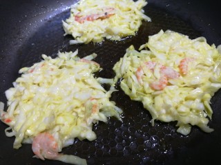 鸡蛋卷心菜饼,煎第二锅，小火慢煎，一面定型后，在上面撒些白芝麻。