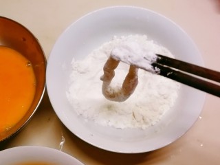 黄金鱿鱼圈,玉米淀粉和面粉混合 取一个鱿鱼圈放入混合面粉里滚一圈 