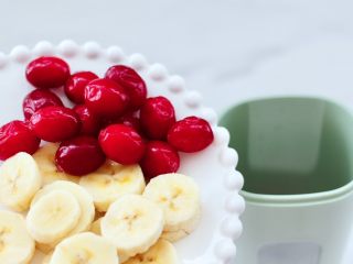 香蕉蔓越莓奶昔,蔓越莓冲洗干净后和香蕉片一起放入榨汁杯里。