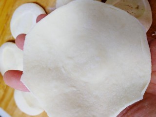 包子【茴香猪肉+西葫芦鸡蛋】,擀成比手掌宽的圆形面皮，中间厚一点点，边上薄一点。