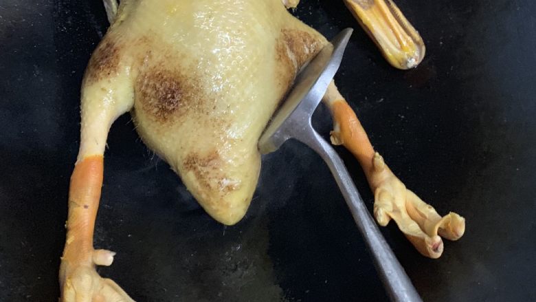 白切鸭,用铲子把鸭腿一边摁到锅面摩擦。