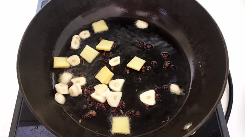红烧三文鱼,利用锅里的余油煸炒花椒粒，姜片和蒜片