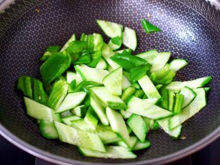 鸭蛋黄瓜炒双椒,另起锅倒入剩下的1勺花生油烧热，先爆香葱碎，再放入黄瓜片快速翻炒均匀。