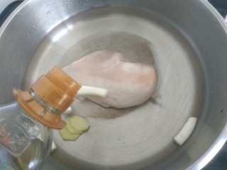 手撕鸡胸肉,锅中放入适量清水，放入鸡胸肉，加入葱段，加入一勺料酒