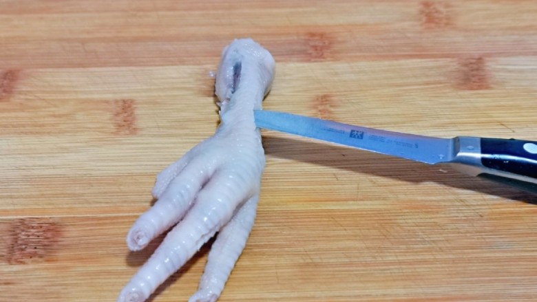 百香果柠檬鸡爪,泡好的鸡爪去骨，首先将根部用水果刀划断开，再鸡爪背上划一刀，如图。
