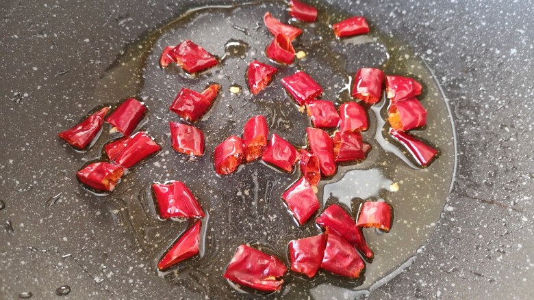 酸豆角炒鸡胗,炒锅内倒适量的食用油烧热，下入干红辣椒中火炒香。