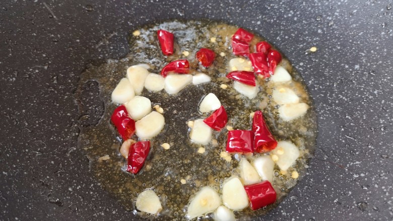 丝瓜炒毛豆,锅底留余油，下入干红辣椒和蒜片炒香。