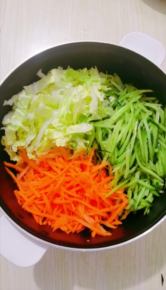白菜拌黄瓜丝,把胡萝卜，黄瓜，白菜丝放入盆里