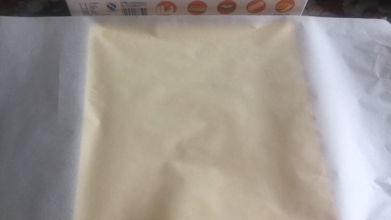 黄桃奶油蛋糕卷,上下均盖上一层油纸，防止蛋糕卷暴露在空气中失去水份。