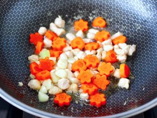 鸡丁莴苣小炒@小兔子饭团,大火快速翻炒至鸡丁变色，加入大蒜片和胡萝卜，继续快速翻炒片刻。