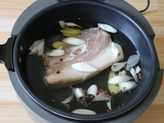 回锅肉,将猪皮洗干净的猪肉整块放入锅中，加入适量冷水，放入大葱、一半的姜片、花椒、料酒；