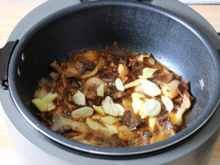 回锅肉,加入郫县豆瓣酱炒匀上色后再倒入姜片、蒜片煸炒出香味；