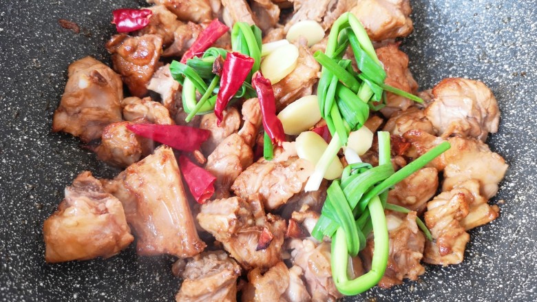 红烧鸭肉,加入小葱、干红辣椒、八角和生姜炒香。