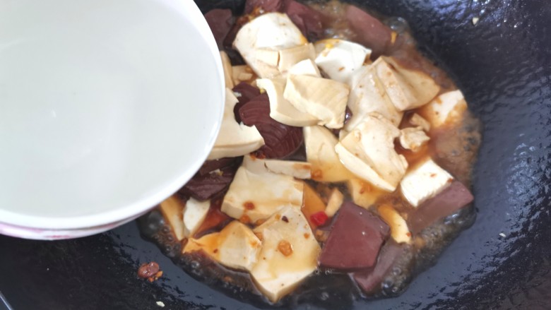 猪血炖豆腐,倒入适量清水，水开烧2分钟