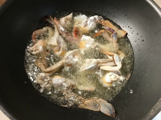 螃蟹炒年糕,锅里热油，放入螃蟹块，炸至定型变色