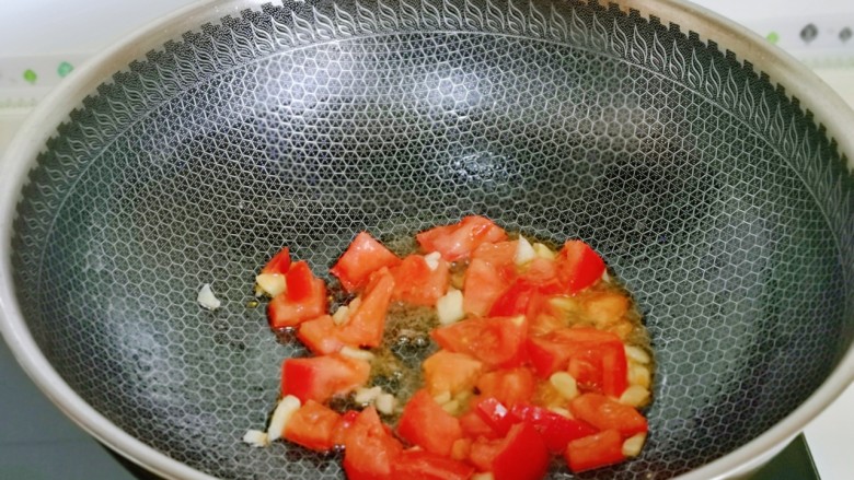 番茄炒丝瓜,起油锅，加入蒜末炒香，再加入切好的番茄翻炒。