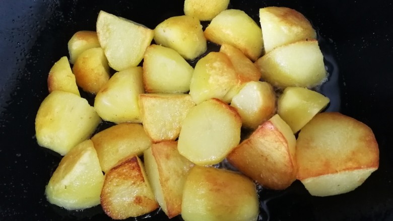 香酥小土豆,2分钟后挨着锅的那面土豆已经煎焦，给它翻个面，继续文火煎2分钟。