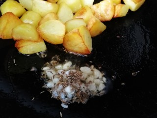 香酥小土豆,把土豆推到锅的一边，放入切好蒜末和孜然粒，用锅里剩余的油小火炒香。