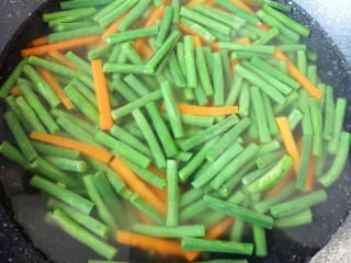 凉拌豇豆,锅内放水烧开，下入豇豆和胡萝卜，烧开以后焯水2分钟关火。