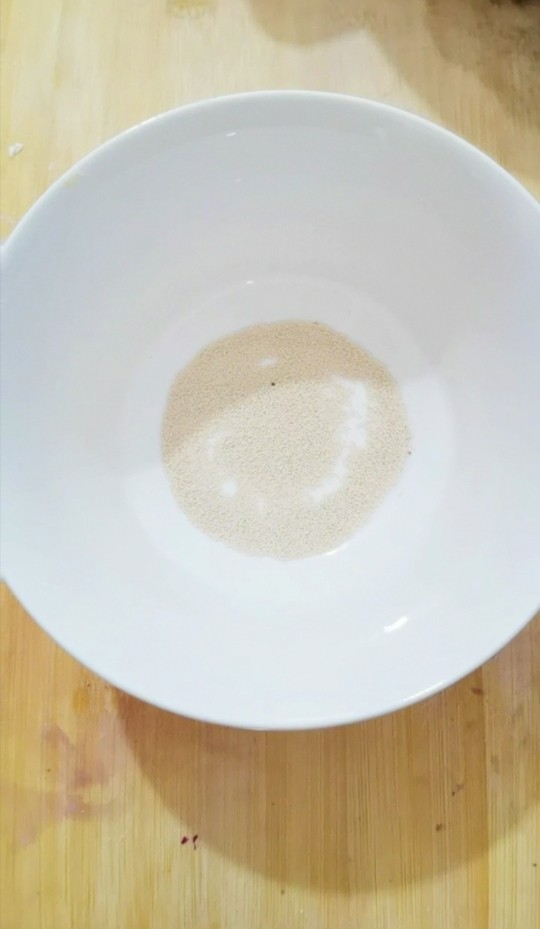紫薯发面豆沙饼,碗里加入酵母粉，用温水化开