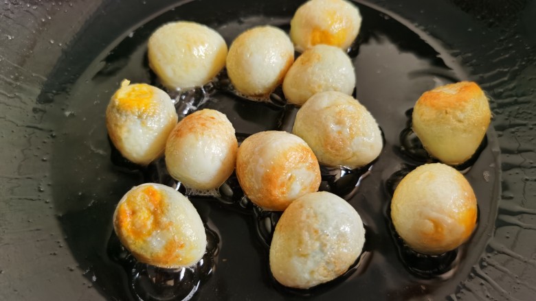 鹌鹑蛋焖土豆,不停的晃动炒锅，让鹌鹑蛋的外皮煎成金黄色。