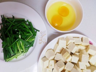 豆腐炒鸡蛋,豆腐切小方块，韭菜洗净切段，鸡蛋打入碗里。