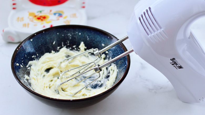 腰果酥小饼干,先用上豪打蛋器的专用黄油头搅拌均匀，这样可以避免打发时黄油和白糖到处飞溅，这个时候用打蛋器开始打发至黄油蓬松发白羽化的状态。