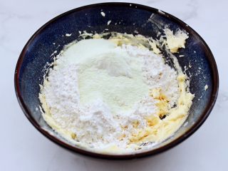 腰果酥小饼干,这个时候加入过筛的低筋面粉和奶粉，泡打粉，所有的食材用刮刀拌匀。