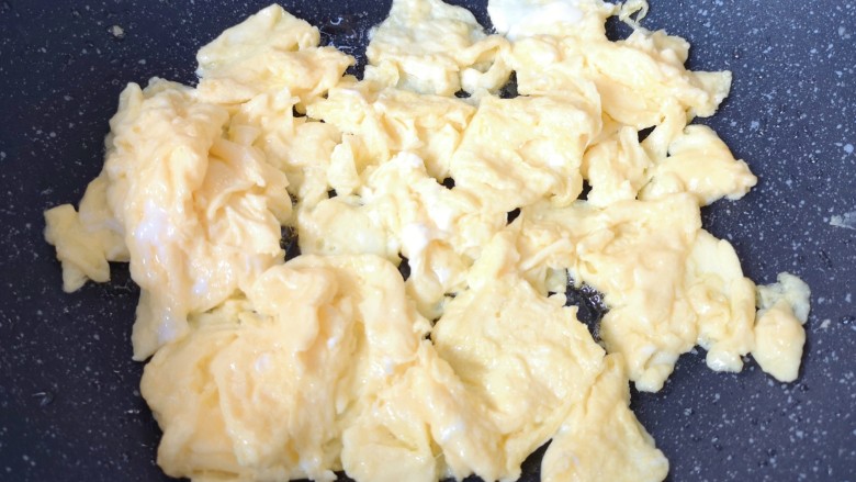 白玉菇炒鸡蛋,待蛋液底部凝固以后用铲子轻轻推动翻炒，炒熟的鸡蛋盛出备用。