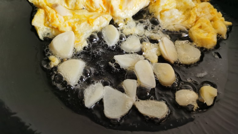 白玉菇炒鸡蛋,将炒好的鸡蛋拨到一边，加入蒜片爆香。