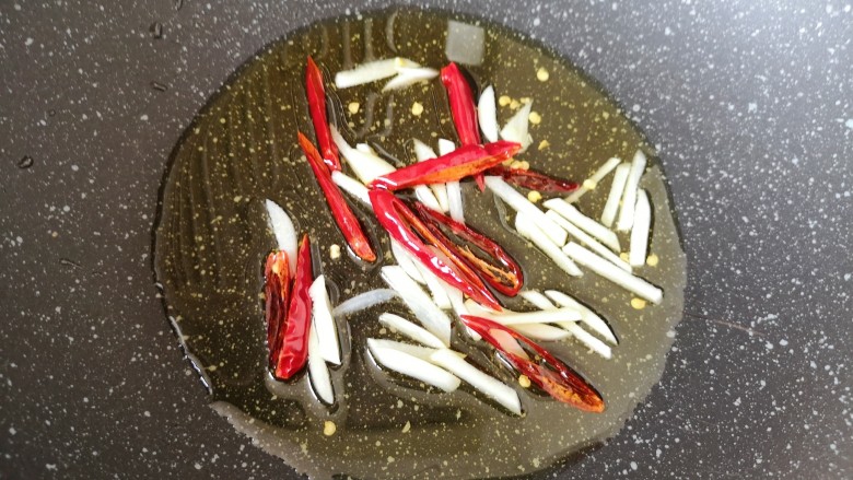 韭菜炒千张,炒锅内倒适量的食用油烧热，下入大蒜和干红辣椒小火炒香。