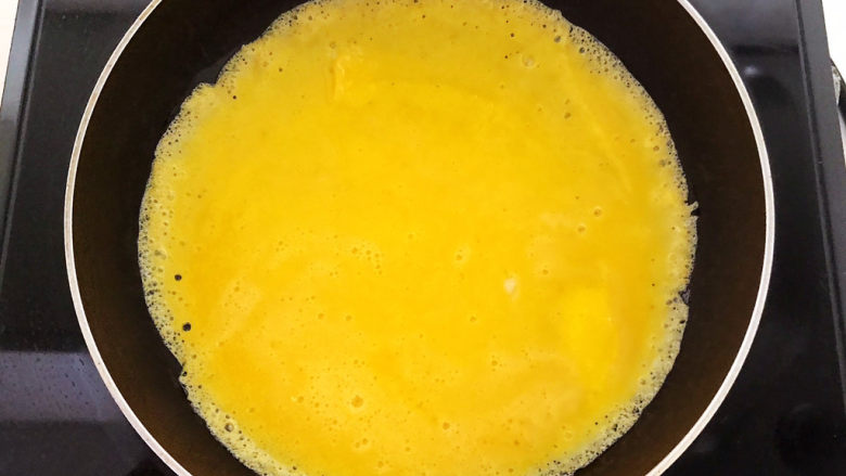 白玉菇炒鸡蛋,炒锅烧热后加入鸡蛋液，煎成鸡蛋饼