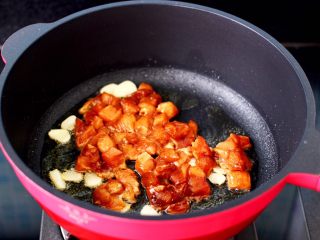 鸡丁黄瓜盖浇饭,马 克西姆微压锅倒入花生油烧热，先爆香蒜片后，再倒入腌制好的鸡丁。