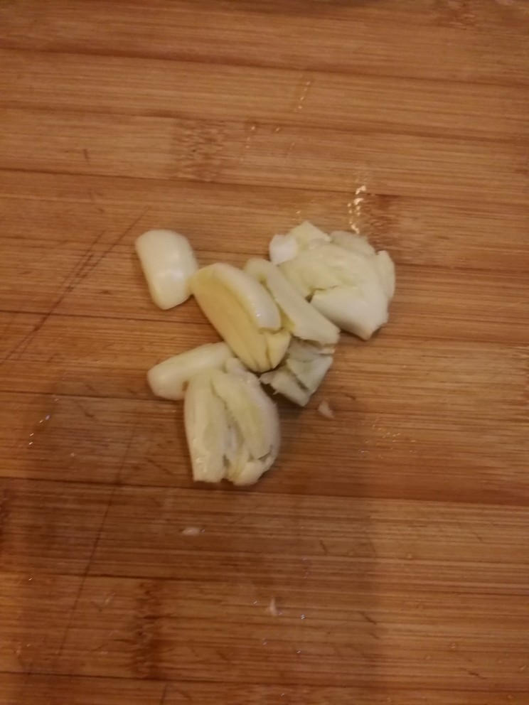 四季豆炒肉丝,蒜瓣用刀拍碎备用。