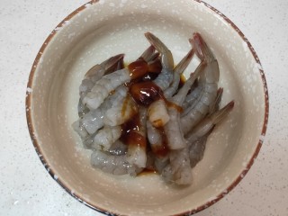 黄金土豆虾球,把剥好的虾倒入碗中再依次放入耗油，酱油，盐，胡椒粉