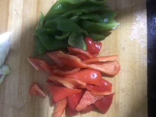 家常烧豆腐,把青椒和红椒先从中间切开成两片，再切成粗条，然后再切成三角形的块状