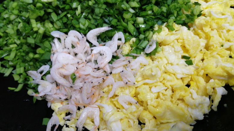 韭菜锅贴,把韭菜和虾皮放入煎过鸡蛋的锅里。