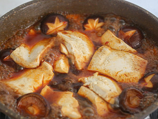 家常烧豆腐,加入豆腐和蒜头焖煮一会稍微翻一下，淋入淀粉水勾芡，起锅，放上葱丝即可上桌。