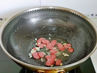 红烧素鸡,起油锅，加入蒜炒香，再加入香肠片翻炒。