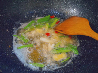 香辣螃蟹,剩下的油里倒入准备好的蒜泥、姜片、红米椒、葱段翻炒