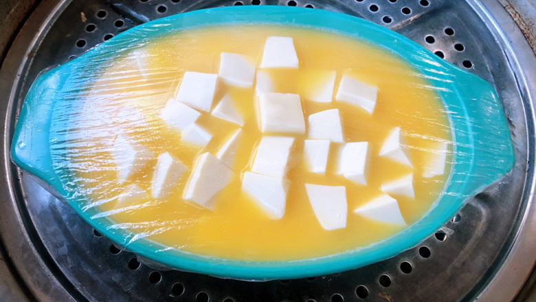 豆腐蒸蛋,盖上保鲜膜放入烧开的蒸锅中大火蒸十分钟