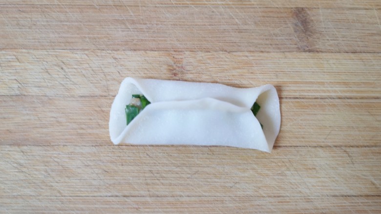 韭菜锅贴,在饺子皮的边缘抹一些水，对折捏紧，一个锅贴就包好了。