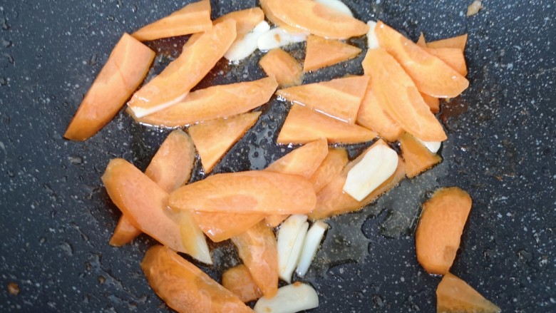 丝瓜炒虾仁,锅底留余油烧热，下入蒜片炒香，下入胡萝卜翻炒至变色。
