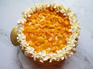 红丝绒水果裸蛋糕,继续放上第二层蛋糕片，抹上一层奶油，放上小块的芒果，用裱花袋里的奶油继续在蛋糕边上挤出奶油花。