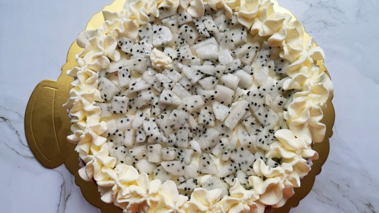 红丝绒水果裸蛋糕,抹上一层奶油，放上小块的火龙果，用裱花袋里的奶油在蛋糕边上挤出奶油花。